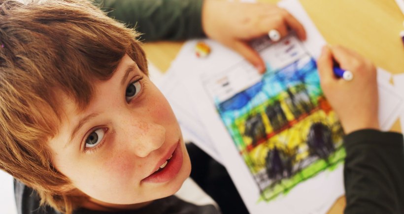 A smiling young lady with short hair enjoys drawing various shapes and adding lots of bright colours, expressing herself through art.